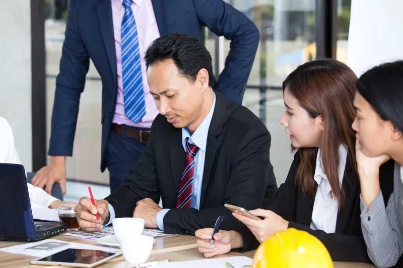 Project management consultancy team reviewing plans and timelines during a business meeting in Singapore.